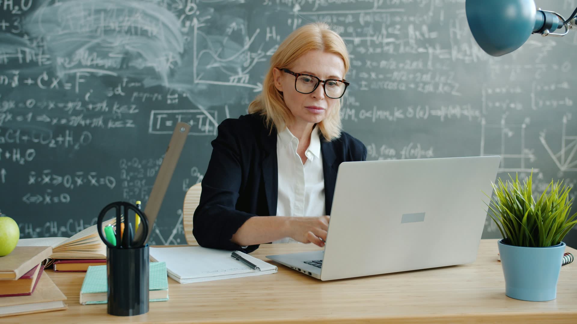 Woman working on a laptop in front of a chalkboard